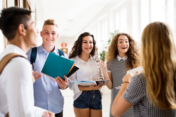 High school teens standing around holding books