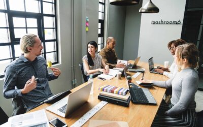 Five people sitting in a conference room discussing marketing their business