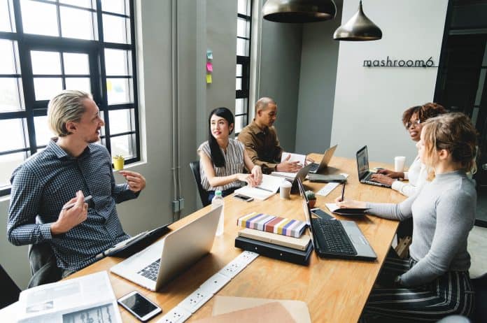 Five people sitting in a conference room discussing marketing their business