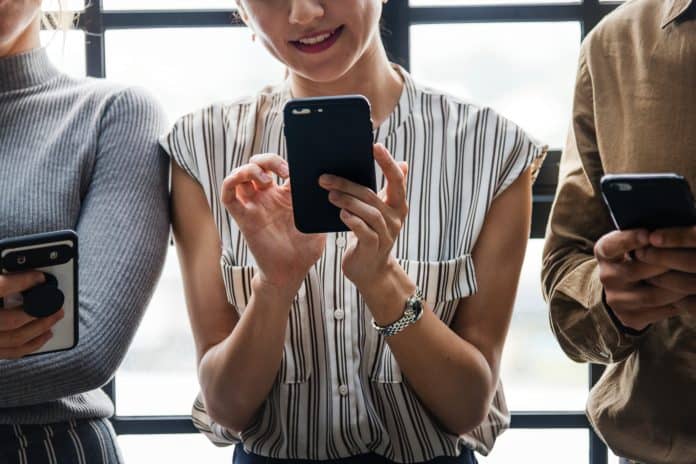 Three people scrolling through their phones.