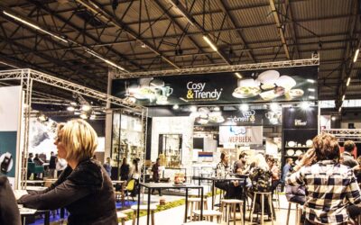 People sitting at tables at a trade show. Tradeshow banners are displayed above them