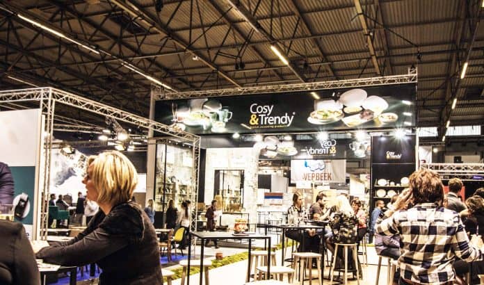 People sitting at tables at a trade show. Tradeshow banners are displayed above them