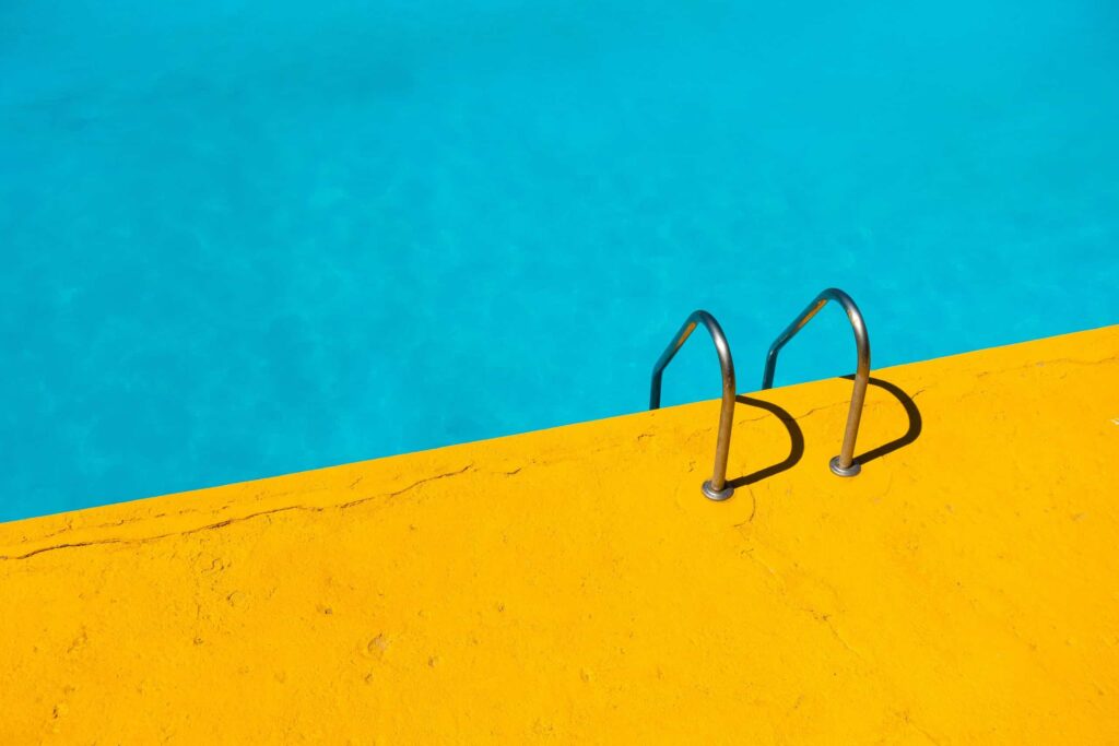 A picture of a pool and ground with the color combination of blue and yellow