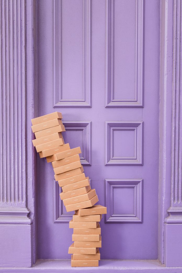 stack of shipping boxes leaning on a purple doorway