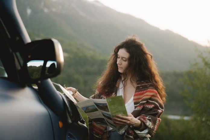 Person looking at a travel brochure by the mountains