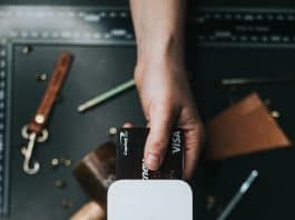 person holding Visa card and white POP display