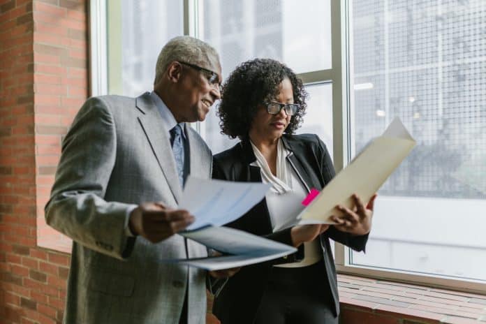 Two people holding folders in an office setting