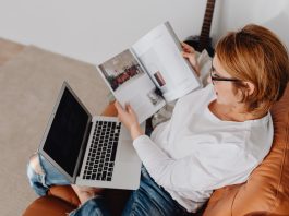 Person holding a product catalog and laptop on a seat