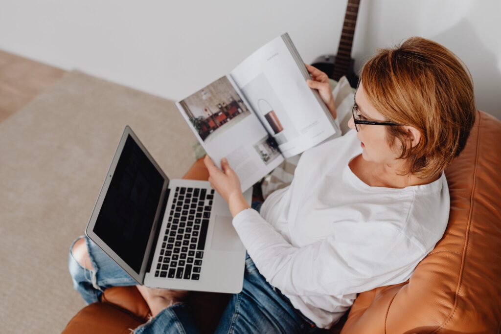 Person holding a product catalog and laptop on a seat