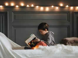 Child holding a childrens book cover idea book on a white surface