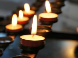 A line of lit tea light candles in the dark