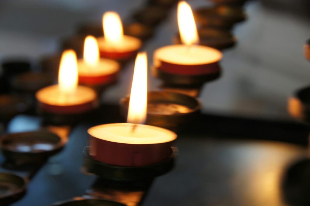 A line of lit tea light candles in the dark