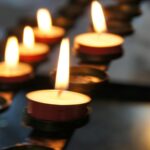 A line of lit tea light candles in the dark