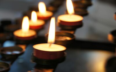 A line of lit tea light candles in the dark