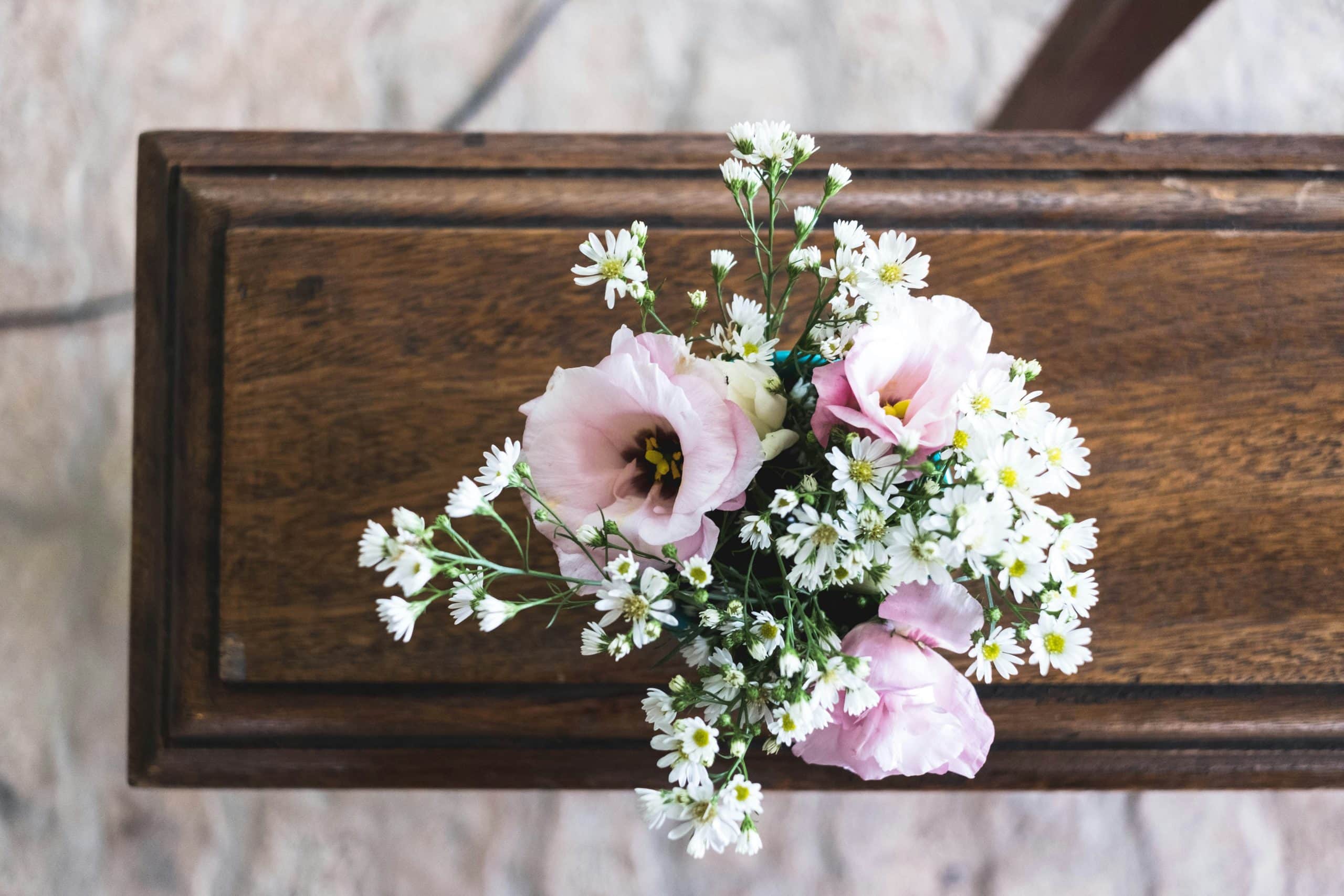 A wooden casket with a bouquet of flowers on top